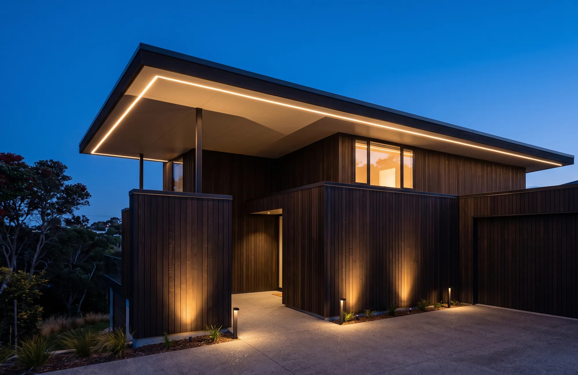 A dark-timber home at blue hour with architectural LED lighting grazing the cladding